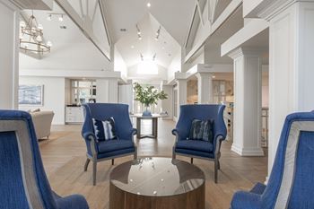 A modern living room with blue chairs and a glass table